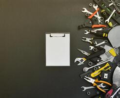 trousse à outils de bricoleur sur une table en bois noire. de nombreuses clés et tournevis, piles et autres outils pour tous types de travaux de réparation ou de construction. outils de réparateur photo