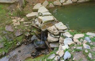 proche en haut de une petit cascade effusion plus de mousse couvert rochers dans régional parc. Fait main rivière cascade photo