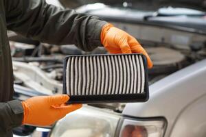 gros plan les mains du mécanicien tiennent le tampon de filtre à air du moteur de voiture pour vérifier. concept, voiture cassée, service de réparation et d'entretien. le filtre à air sale doit être changé pour être hygiénique. photo