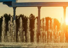 fontaines illuminé par lumière du soleil à le coucher du soleil ou lever du soleil dans le parc à heure d'été. photo