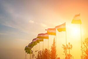 drapeaux de Ouzbékistan agitant sur une le coucher du soleil ou lever du soleil spectaculaire ciel Contexte. photo