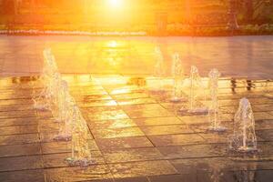 petit fontaines sur le trottoir, illuminé par lumière du soleil à le coucher du soleil ou lever du soleil à heure d'été. photo