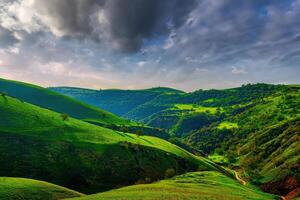 collines et montagnes couvert avec Jeune vert herbe et illuminé par le Soleil sur une ensoleillé journée. photo