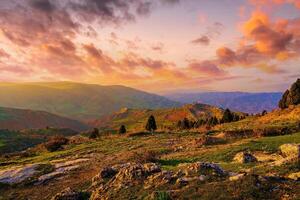 brumeux le coucher du soleil ou Aube dans le montagnes couvert avec herbe et nuageux spectaculaire ciel. photo