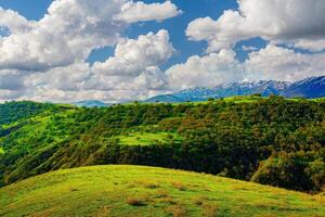 collines et montagnes couvert avec Jeune vert herbe et illuminé par le Soleil sur une ensoleillé journée. photo