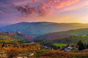 brumeux le coucher du soleil ou Aube dans le montagnes couvert avec herbe et nuageux spectaculaire ciel. photo