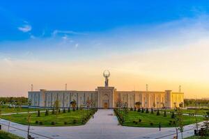 Ouzbékistan, Tachkent - avril 25, 2023 le territoire de le parc Nouveau Ouzbékistan avec monument de indépendance dans le forme de une stèle avec une humo oiseau à crépuscule. photo