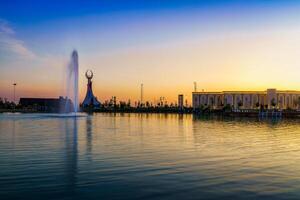 Ouzbékistan, Tachkent - avril 25, 2023 le territoire de le parc Nouveau Ouzbékistan avec monument de indépendance dans le forme de une stèle avec une humo oiseau, étang et Fontaine à crépuscule. photo