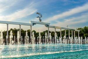 Mémorial et Lignes de fontaines illuminé par lumière du soleil à le coucher du soleil ou lever du soleil dans le indépendance carré à heure d'été, tachkent. photo