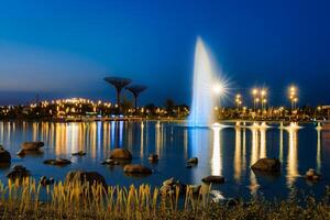 flou Fontaine l'eau les flux dans un artificiel Lac dans une nuit parc avec lanternes et décorations. photo