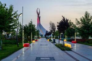 Ouzbékistan, Tachkent - mai 25, 2023 illuminé monument de indépendance dans le forme de une stèle avec une humo oiseau dans le Nouveau Ouzbékistan parc à soir. photo