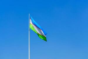 drapeau de Ouzbékistan agitant sur une jour ciel Contexte. photo