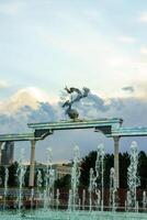 Mémorial et Lignes de fontaines illuminé par lumière du soleil à le coucher du soleil ou lever du soleil dans le indépendance carré à heure d'été, tachkent. photo