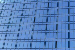 fragment de une moderne Bureau bâtiment. abstrait géométrique Contexte. partie de le façade de une gratte-ciel avec verre les fenêtres. photo