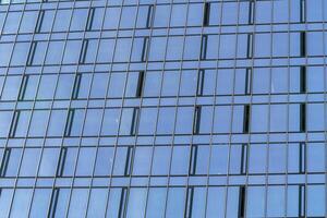 fragment de une moderne Bureau bâtiment. abstrait géométrique Contexte. partie de le façade de une gratte-ciel avec verre les fenêtres. photo
