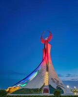 Ouzbékistan, Tachkent - janvier 4, 2023 illuminé monument de indépendance dans le forme de une stèle avec une humo oiseau dans le Nouveau Ouzbékistan parc à nuit. photo