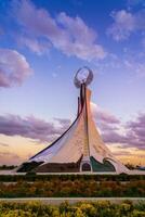 Ouzbékistan, Tachkent - octobre 4, 2023 monument de indépendance dans le forme de une stèle avec une humo oiseau sur une crépuscule avec Cliody ciel dans le Nouveau Ouzbékistan parc. photo