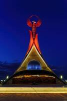 Ouzbékistan, Tachkent - octobre 4, 2023 illuminé monument de indépendance dans le forme de une stèle avec une humo oiseau dans le Nouveau Ouzbékistan parc à la nuit dans l'automne. photo