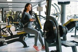 magnifique Jeune femme envoyer des SMS et social la mise en réseau tandis que dans une salle de sport. photo