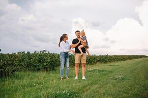 content famille avec peu fille dépenses temps ensemble dans ensoleillé champ photo