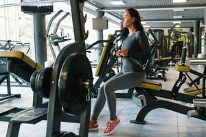 magnifique Jeune femme envoyer des SMS et social la mise en réseau tandis que dans une salle de sport. photo