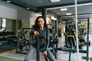 jolie hispanique Jeune femme Faire certains crossfit des exercices avec une corde à une salle de sport. photo