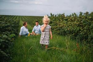 content famille en marchant dans le parc. maman, papa et fille marcher en plein air, Parents en portant le bébé les filles mains. enfance, la parentalité, famille obligations, mariage concept. photo