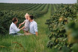 le fille étreindre Parents sur la nature. maman, papa et fille tout-petit, marcher dans le herbe. content Jeune famille dépenses temps ensemble, dehors, sur vacances, en plein air. le concept de famille vacances photo