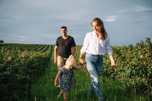 content famille avec peu fille dépenses temps ensemble dans ensoleillé champ. photo