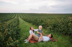 le fille étreindre Parents sur la nature. maman, papa et fille tout-petit, marcher dans le herbe. content Jeune famille dépenses temps ensemble, dehors, sur vacances, en plein air. le concept de famille vacances photo