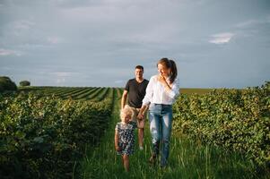 content famille avec peu fille dépenses temps ensemble dans ensoleillé champ. photo