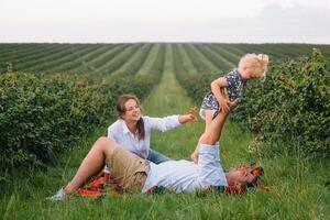 content famille en marchant dans le parc. maman, papa et fille marcher en plein air, Parents en portant le bébé les filles mains. enfance, la parentalité, famille obligations, mariage concept. photo