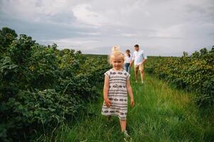 content famille en marchant dans le parc. maman, papa et fille marcher en plein air, Parents en portant le bébé les filles mains. enfance, la parentalité, famille obligations, mariage concept. photo