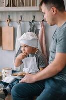 Jeune homme et le sien fils avec four feuille dans cuisine. père avec peu fils sur le cuisine photo