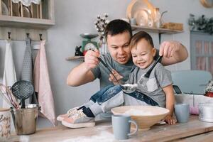 Jeune homme et le sien fils avec four feuille dans cuisine. père avec peu fils sur le cuisine. photo