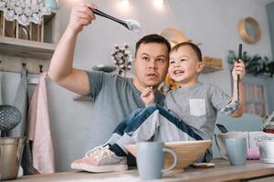 Jeune homme et le sien fils avec four feuille dans cuisine. père avec peu fils sur le cuisine. photo