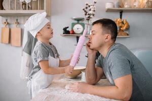 Jeune homme et le sien fils avec four feuille dans cuisine. père avec peu fils sur le cuisine. photo