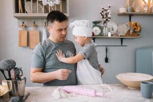 Jeune homme et le sien fils avec four feuille dans cuisine. père avec peu fils sur le cuisine. photo