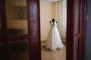 magnifique de la mariée blanc mariage robe bloque près le lit dans une Hôtel pièce avec fleurs à le bas. de mariée Matin avant la cérémonie photo