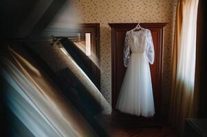 magnifique de la mariée blanc mariage robe bloque près le lit dans une Hôtel pièce avec fleurs à le bas. de mariée Matin avant la cérémonie photo