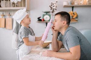 Jeune homme et le sien fils avec four feuille dans cuisine. père avec peu fils sur le cuisine. photo