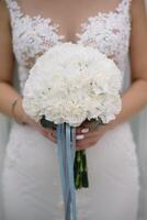 la mariée des stands dans une blanc mariage robe avec une bouquet de fleurs photo