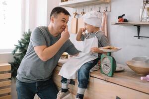 Jeune homme et le sien fils avec four feuille dans cuisine. père avec peu fils sur le cuisine. photo