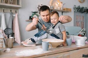 Jeune homme et le sien fils avec four feuille dans cuisine. père avec peu fils sur le cuisine. photo