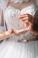 demoiselle d'honneur en train de préparer la mariée pour mariage journée. demoiselle d'honneur portion la mariée boucler laçage sa mariage blanc robe avant cérémonie. luxe de mariée robe proche en haut. mariage Matin des moments détails concept. photo