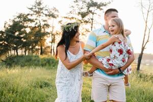 content famille de Trois les personnes en marchant le herbe dans le parc photo