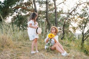 élégant mère et Beau fille ayant amusement sur le la nature. content famille concept. beauté la nature scène avec famille Extérieur mode de vie. famille repos ensemble. bonheur dans famille vie. les mères journée photo