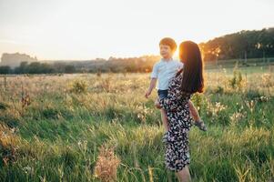 élégant mère et Beau fils ayant amusement sur le la nature. content famille concept. beauté la nature scène avec famille Extérieur mode de vie. content famille repos ensemble. bonheur dans famille vie. les mères journée photo