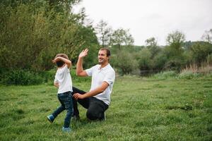 content homme et le sien enfant ayant amusement en plein air. famille mode de vie rural scène de père et fils dans le coucher du soleil lumière du soleil. concept de une content famille. photo