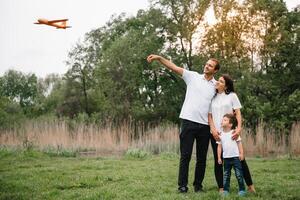 content famille mère père et enfant fils sur la nature sur le coucher du soleil. maman, papa et enfant en riant et étreindre, profiter la nature dehors. ensoleillé jour, bien ambiance. concept de une content famille. photo